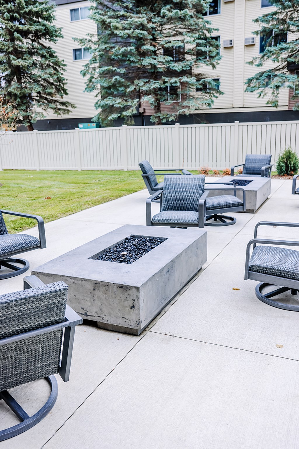 the outdoor seating area of a building with chairs and a fire pit
