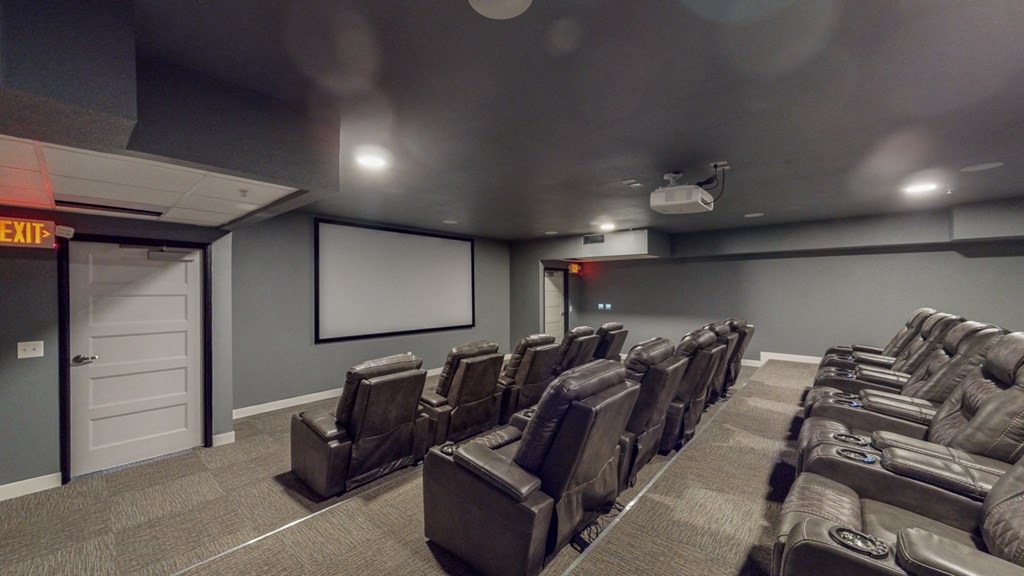 a theater room with a projector screen and chairs
