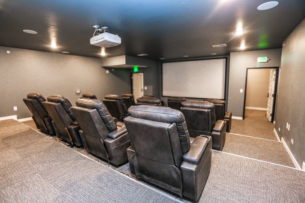 a large theater room with leather chairs and a projector screen