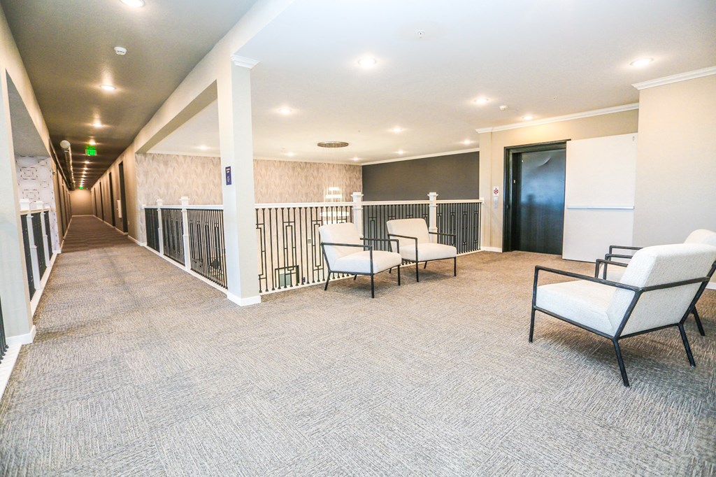 a spacious living room with white chairs and a balcony