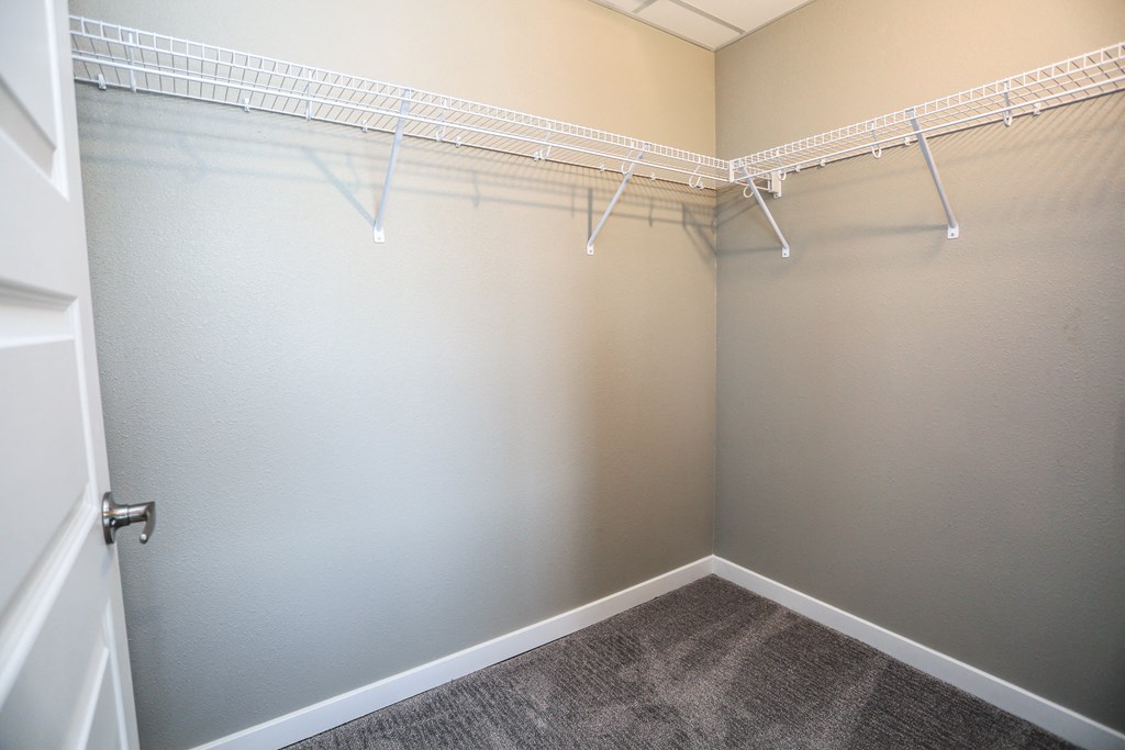 an empty closet with white hanging rods on the wall
