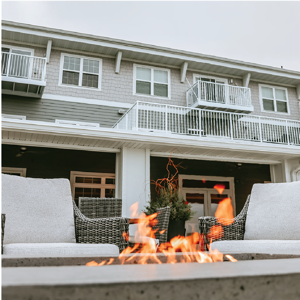 a backyard fire pit with two chairs in front of a house