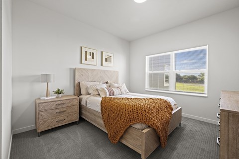 A bedroom with a bed, nightstand, and window.