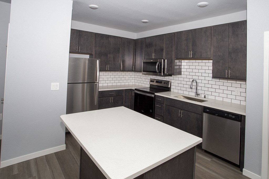 a kitchen with a white counter top and a stainless steel refrigerator