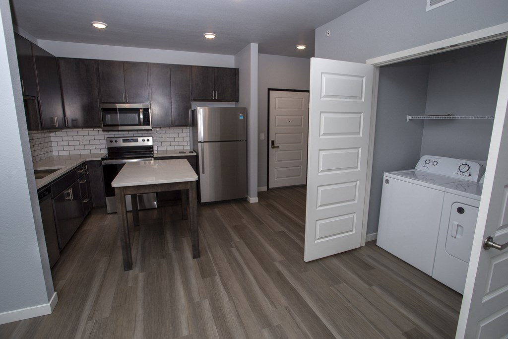 a kitchen with stainless steel appliances and a white washer and dryer in it