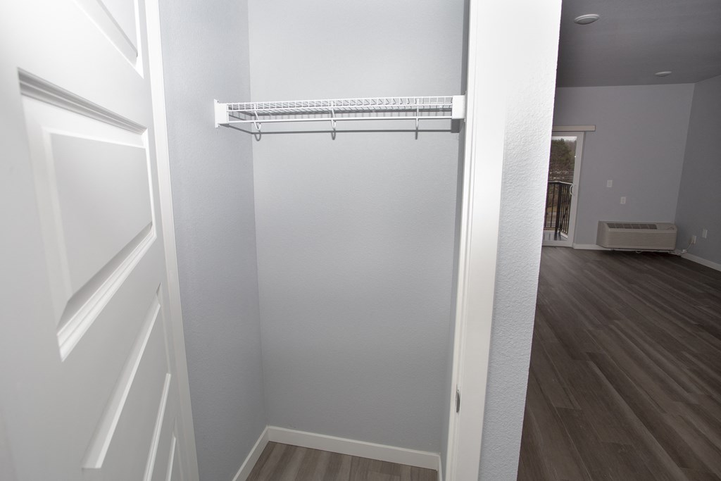 an empty closet in a home with a wooden floor and white walls