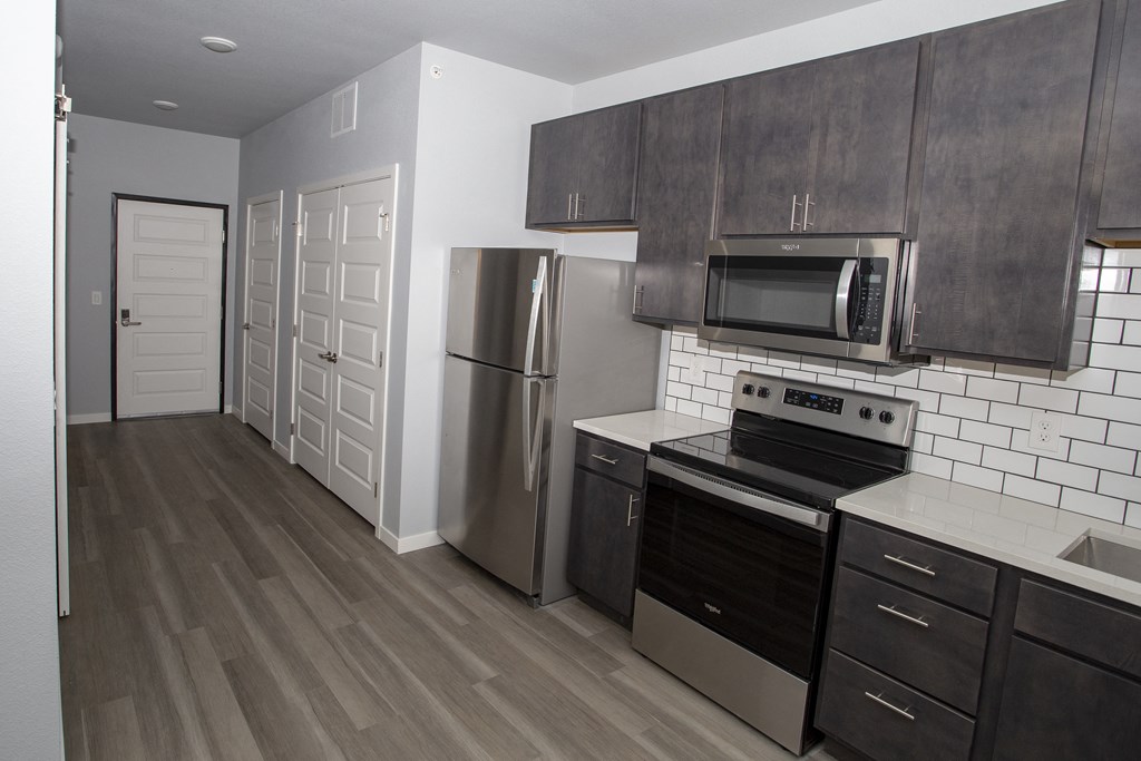 an empty kitchen with stainless steel appliances and wooden cabinets