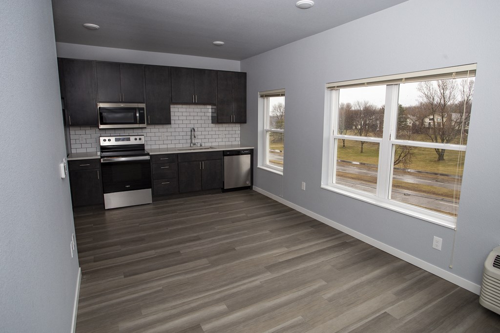 a kitchen with wood floors and black cabinets and a window