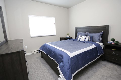 A bedroom with a bed, nightstand, and window.