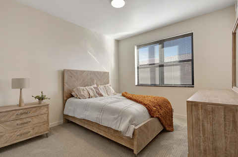 A bedroom with a bed, nightstand, and window.