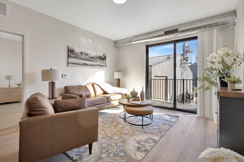 A living room with a brown couch and a painting on the wall.
