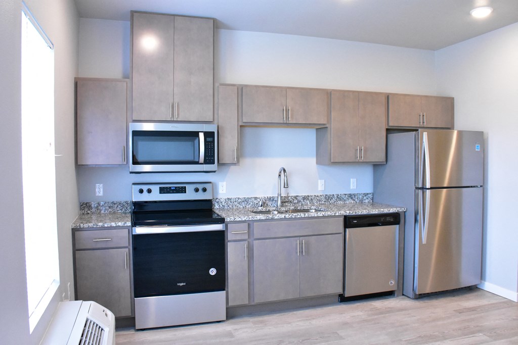 an empty kitchen with stainless steel appliances and granite counter tops
