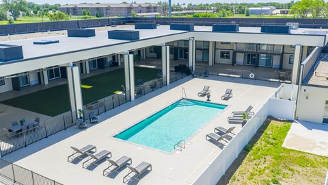 A large outdoor swimming pool surrounded by sun loungers and a white building.