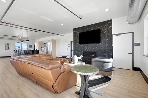 A living room with a brown leather couch and a TV mounted on the wall.