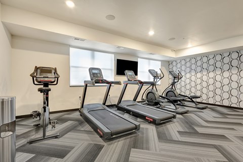 A gym with treadmills, elliptical machines, and other exercise equipment.