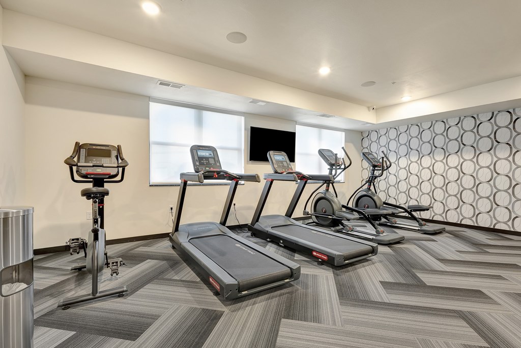 A gym with treadmills, elliptical machines, and other exercise equipment.