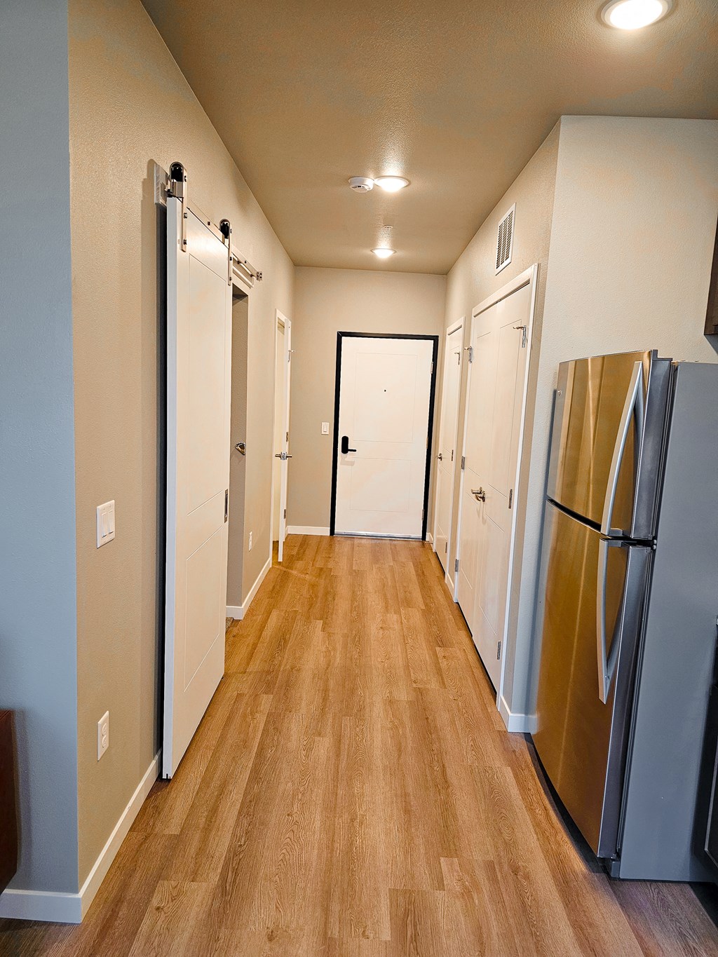 a hallway with a refrigerator and a door to a closet