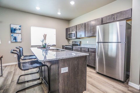 A kitchen with a stainless steel refrigerator and a granite countertop.