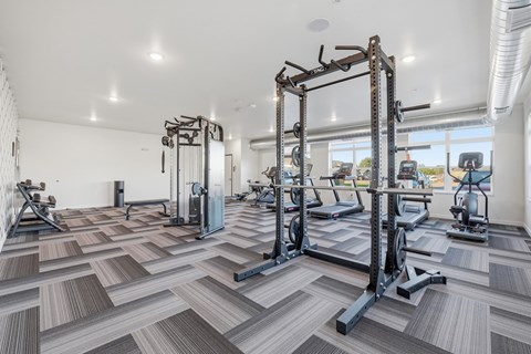 A gym with a variety of equipment including treadmills, weights, and exercise machines.