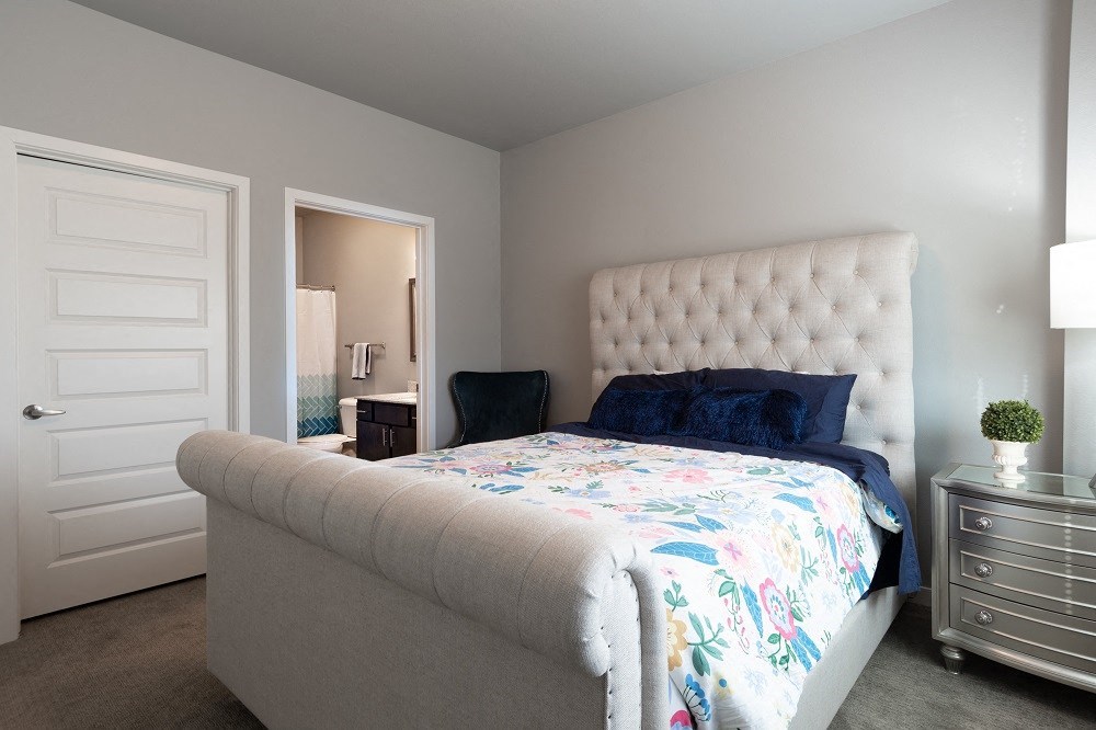 a bedroom with a bed and a couch and a door to a bathroom