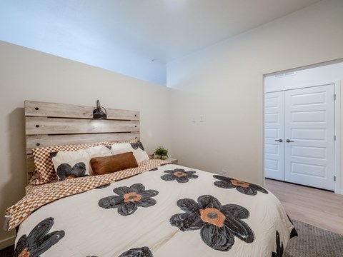 A bedroom with a bed, pillows, and a wooden headboard.
