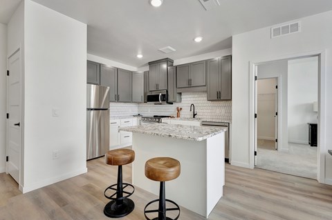 A kitchen with a white counter and bar stools.