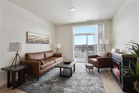 A living room with a brown leather couch, a coffee table, and a fireplace.