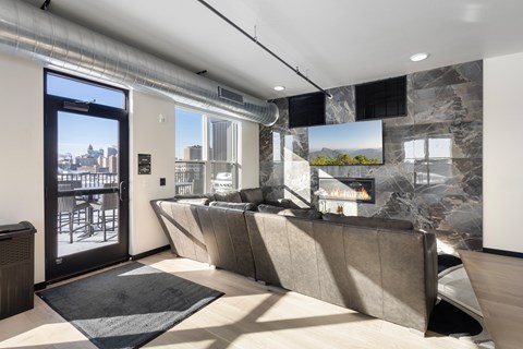 A modern living room with a grey sofa and a large window overlooking the city.