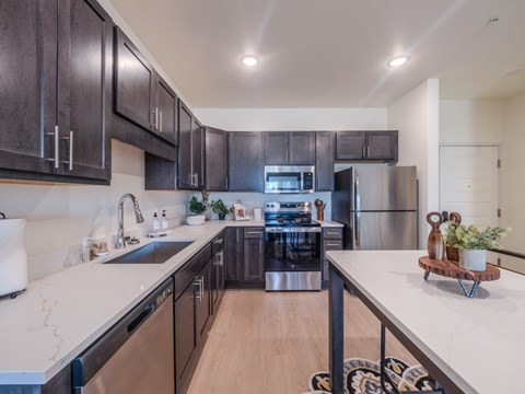 A modern kitchen with dark wood cabinets and stainless steel appliances.