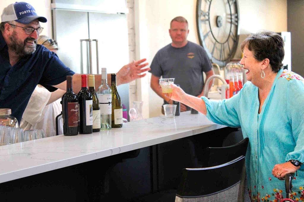 a woman buying wine from a bartender at a bar