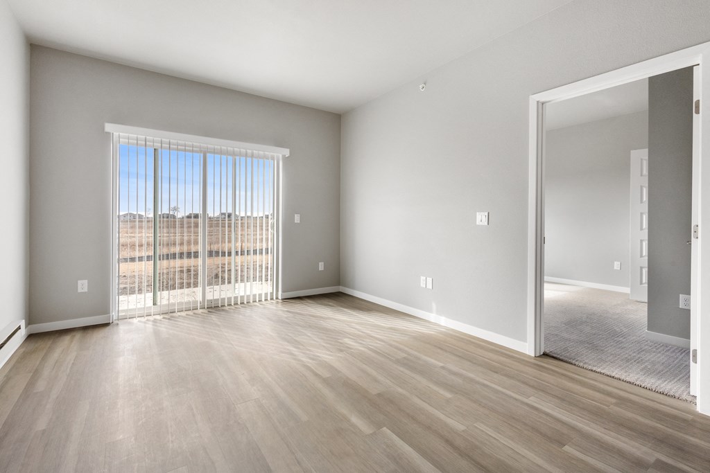 an empty living room with wood floors and a large window