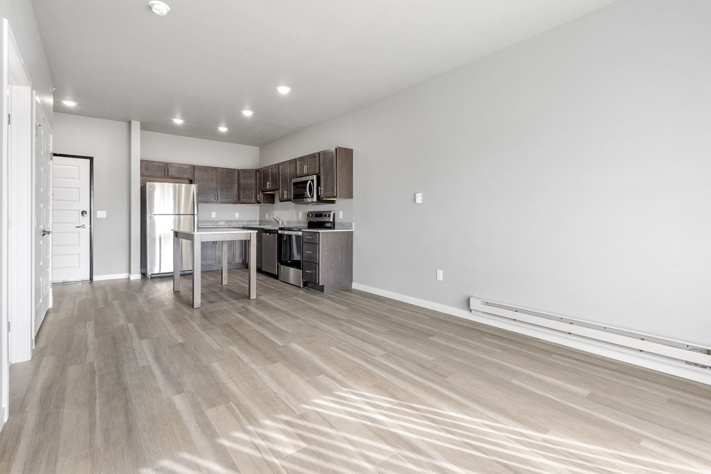 a living room with a kitchen and a wooden floor