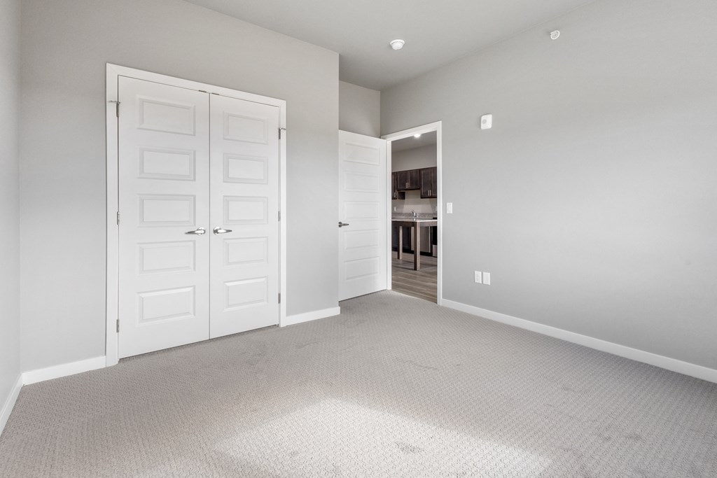 an empty room with a closet and a door to a kitchen