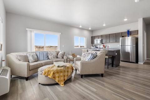 a living room with couches and chairs in front of a kitchen with a