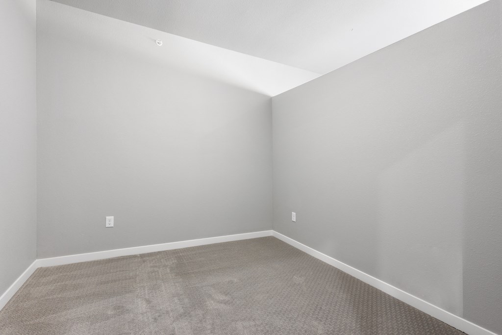 an empty room with carpet and grey walls