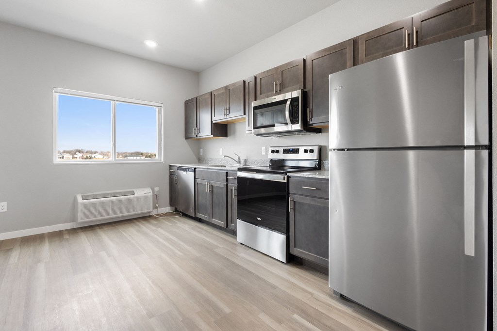 an empty kitchen with stainless steel appliances and a window