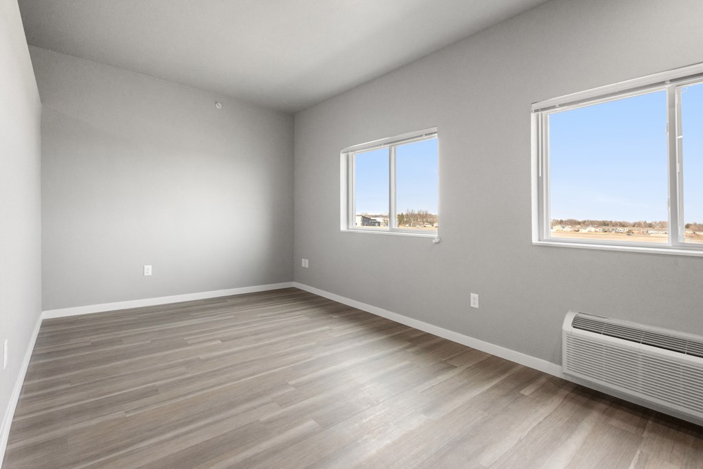 an empty room with wood floors and three windows
