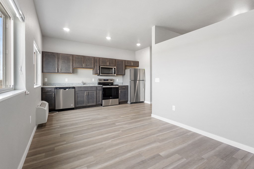the living room and kitchen in a new home with white walls and wood flooring