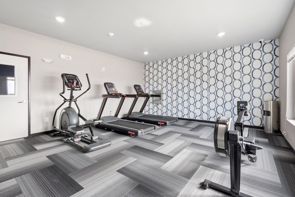 a gym with treadmills and other exercise equipment on a tile floor