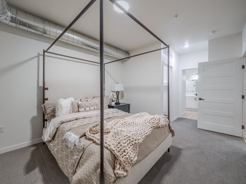 A bedroom with a four poster bed and a carpeted floor.