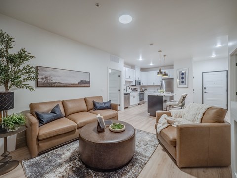 A living room with a brown leather couch and a coffee table in the center.