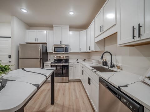 A modern kitchen with white cabinets and stainless steel appliances.