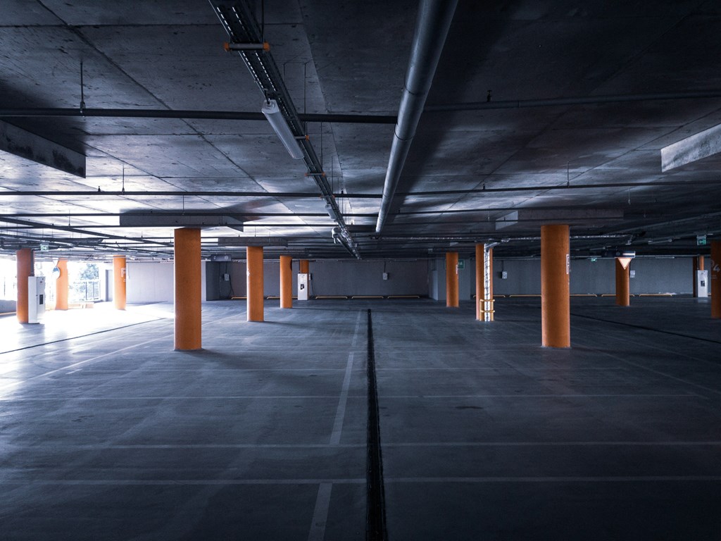 an empty parking garage with orange pillars in it