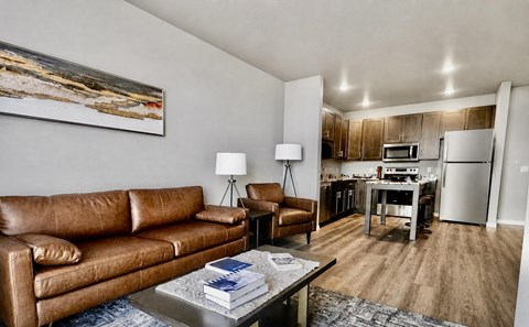 A living room with a brown leather couch and a painting on the wall.
