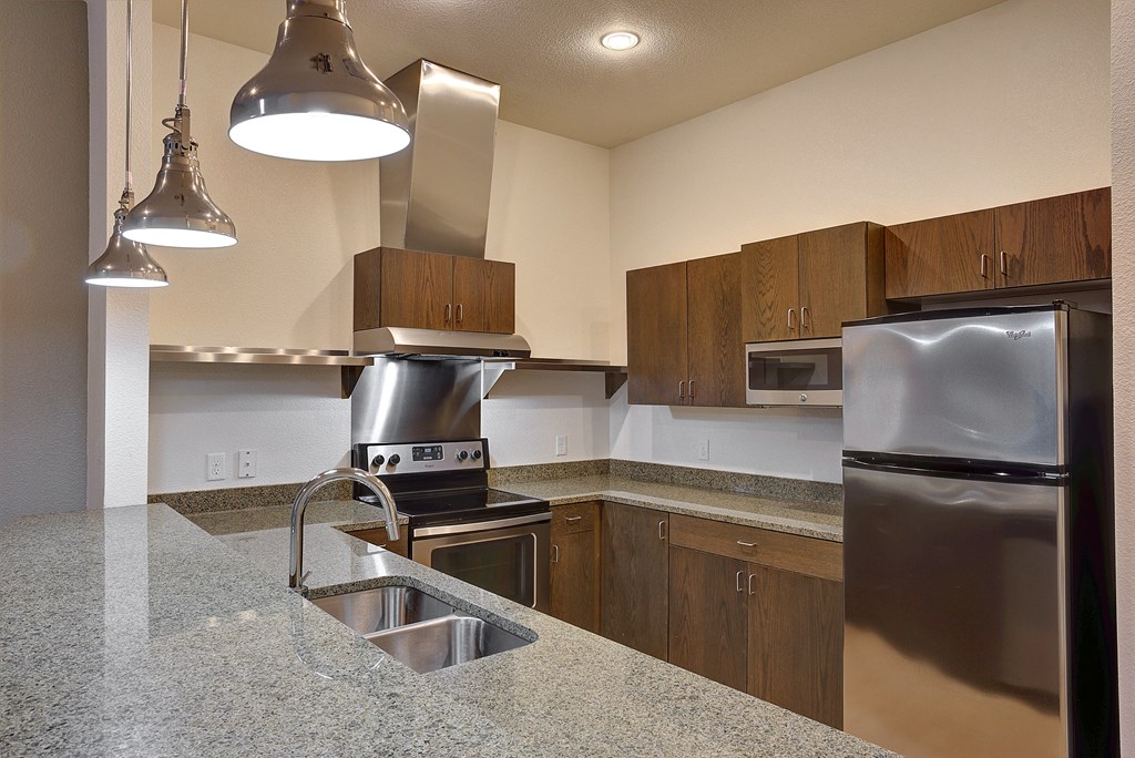 Organic finishes in apartment kitchen with stunning vent hood and stainless steel appliances at The Mosaic on Broadway, San Antonio, TX