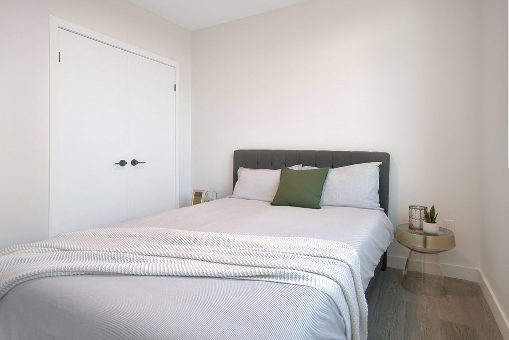 a bedroom with white walls and a bed with white and green pillows