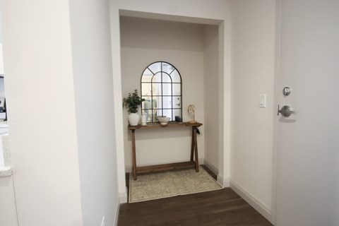 A hallway with a wooden bench and a mirror.