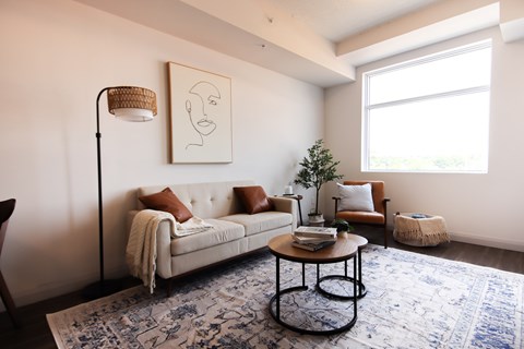 A living room with a white couch, a coffee table, and a large window.