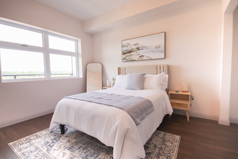 A bedroom with a large bed and a painting on the wall.