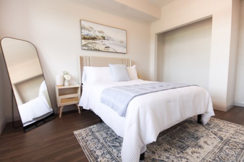 A bedroom with a bed, a nightstand, and a chair.